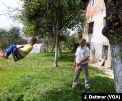 Huso Ahmić, now 72 years old, plays with a grandson in the garden of his family home, which was rebuilt after it was razed in the 1993 attack. His parents died in the blaze.