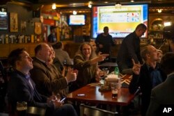 FILE - Russian political experts react as they watch a live telecast of the U.S. presidential election in the Union Jack pub in Moscow, Russia, Nov. 9, 2016. While welcoming Donald Trump's win in the U.S. election, some discount the theory of Trump as Putin's puppet.