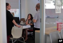 Rosa Franco, director of lending at Neighborhood Trust Federal Credit Union talks with employees at the bank in New York, May 24, 2018.