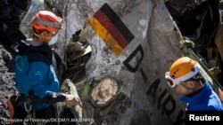 French gendarmes, seen in this picture made available to the press by the French Interior Ministry April 1, 2015, work near debris from wreckage showing a German flag at the crash site of an Airbus A320, near Seyne-les-Alpes. 