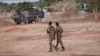 FILE - Burkina Faso army officers patrol near a French armored vehicle parked in Kaya, capital of Burkina Faso's north-central region, after people protested the passage of a large French army convoy in transit to neighboring Niger, Nov. 20, 2021. 