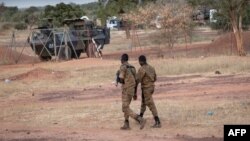 FILE - Burkina Faso army officers patrol near a French armored vehicle parked in Kaya, capital of Burkina Faso's north-central region, after people protested the passage of a large French army convoy in transit to neighboring Niger, Nov. 20, 2021. 