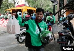 Pengemudi Go-Jek menunjukkan bungkusan makanan yang dipesan oleh pelanggannya di depan sebuah kios makanan, di Jakarta, Indonesia, 13 Juli 2017. (Foto: Reuters/Beawarta)