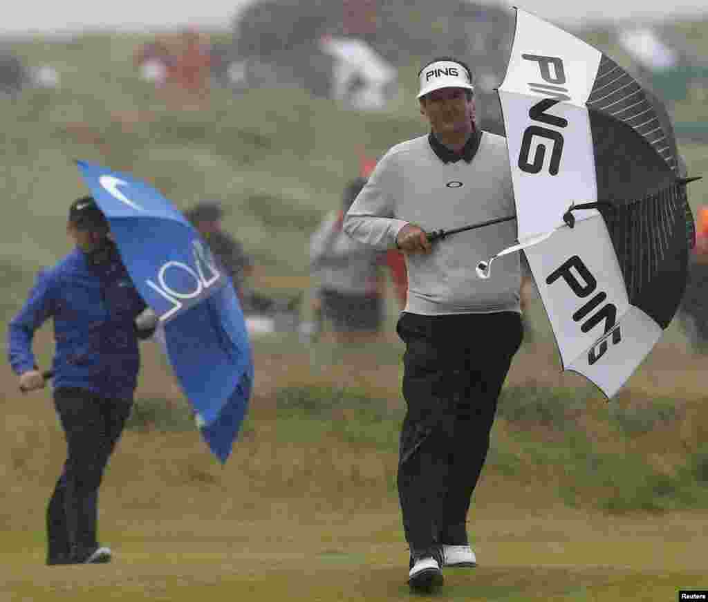 Bubba Watson of the U.S. and Northern Ireland&#39;s Rory McIlroy use umbrellas to shelter from the rain on the 14th hole during the second round of the British Open at Royal Troon, Scotland, Britain.
