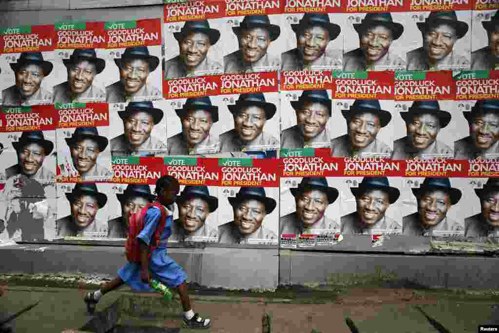 A schoolgirl walks past campaign posters in support of Nigeria&#39;s President Goodluck Jonathan along a road in Ikoyi district in Lagos.