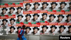 A schoolgirl walks past campaign posters in support of Nigeria's President Goodluck Jonathan along a road in Ikoyi district in Lagos, Feb. 13, 2015. 