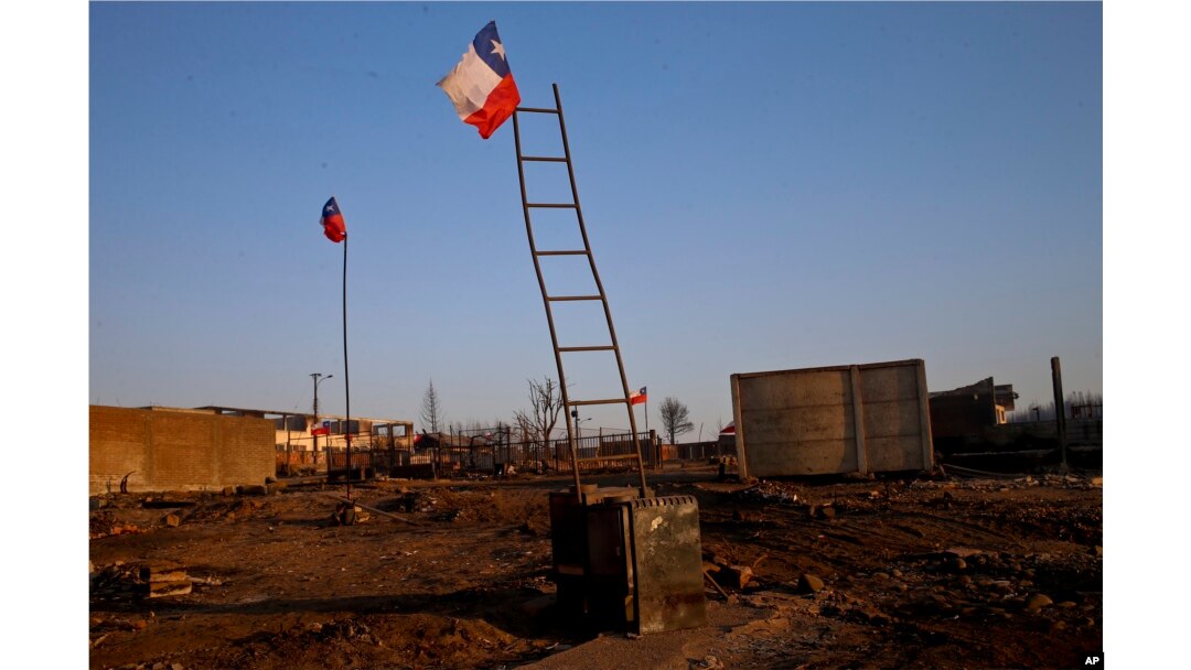 National flags fly over the scorched landscape of Chile's Santa Olga community, Jan. 31, 2017.