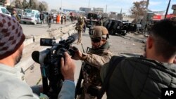 Afghan security police block a TV journalist from filming at the site of bombing attack in Kabul, Afghanistan, Feb. 10, 2021. 
