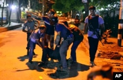 People help an unidentified injured person after a group of gunmen attacked a restaurant popular with foreigners in a diplomatic zone of the Bangladeshi capital Dhaka, Bangladesh, July 1, 2016.