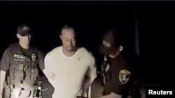Pegolf Tiger Woods dengan tangan terborgol dan dalam pemeriksaan petugas kepolisian dalam foto yang diambil dari video kepolisian di Florida, 29 Mei 2017. 