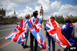 People walk over Westminster Bridge wrapped in Union flags, towards the Queen Elizabeth Tower (Big Ben) and The Houses of Parliament in central London on June 26, 2016.