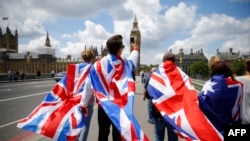 People walk over Westminster Bridge wrapped in Union flags, towards the Queen Elizabeth Tower (Big Ben) and The Houses of Parliament in central London on June 26, 2016. 