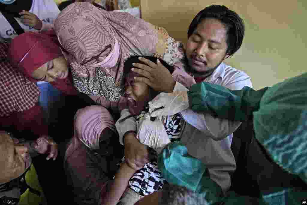 A parent, teachers and a police officer try to calm down a student as he receives a shot of Sinovac COVID-19 vaccine during a vaccination campaign run by Indonesian National Police at a school for children with special needs in Depok on the outskirt of Jakarta.