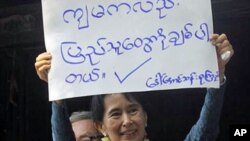 Myanmar's pro-democracy leader Aung San Suu Kyi displays a placard that reads, "I also love the people," to her supporters at the headquarters of her National League for Democracy Party in Yangon, Burma, 14 November 2010