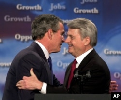 President George Bush, left, and U.S. Sen. Zell Miller, D-Ga., embrace as Bush is introduced at a program on Jobs and Economic Growth at Harrison High School in Kennesaw, Georgia, Feb. 20, 2003.