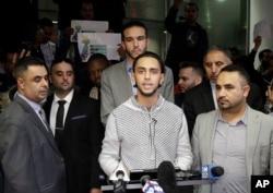Ali Hassan, center, speaks at a news conference after his wife, Shaima Swileh, hidden, arrived at San Francisco International Airport in San Francisco, Dec. 19, 2018.