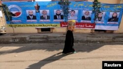 FILE - A woman walks past a campaign banner for the Nour party ahead of parliamentary elections, in Cairo, November 27, 2011.