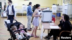 A woman votes while her children wait in their stroller as Ireland holds a referendum on liberalizing its law on abortion, in Dublin, Ireland, May 25, 2018.