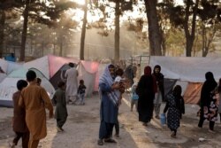 FILE - Displaced Afghan families, fleeing the violence in their provinces, stand near tents in a makeshift shelter at Shahr-e Naw park, in Kabul, Afghanistan, October 4, 2021.