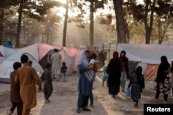 FILE - Displaced Afghan families, fleeing the violence in their provinces, stand near tents in a makeshift shelter at Shahr-e Naw park, in Kabul, Afghanistan, October 4, 2021.