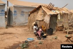 FILE - A woman takes care of her child in a camp sheltering internally displaced people (IDPs) next to the M'Poko international airport in Bangui, Central African Republic, Feb. 13, 2016.