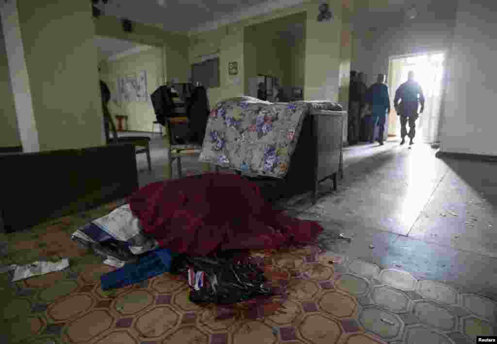 The body of a biology teacher killed by recent shelling lies covered in a school hall in Donetsk, eastern Ukraine, Oct. 1, 2014.