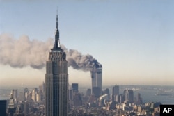 FILE - In this Sept. 11, 2001 photo, the twin towers of the World Trade Center burn behind the Empire State Building in New York after terrorists crashed two planes into the towers causing both to collapse.