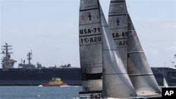 Two 12-meter America's Cup yachts sail past the USS Ronald Reagan in San Diego Harbor, 11 May 2010