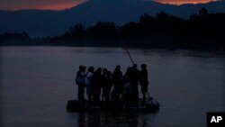 Central American migrants stand on a raft to cross the Suchiate River from Guatemala to Mexico, as the Tacana volcano stands tall near Ciudad Hidalgo, Mexico, early Monday, June 10, 2019. Mexican and U.S. officials reached an accord late Friday that calls on Mexico to crackdown o