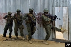 FILE - Somali soldiers search through homes for al-Shabaab fighters, during an operation in Ealsha Biyaha, Somalia, June, 2, 2012.
