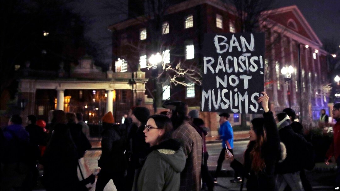 FILE - Several hundred people march past the gates of Harvard Yard at Harvard University while protesting the travel ban in Cambridge, Mass., March 7, 2017. 