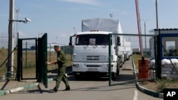 FILE - A Russian border guard opens a gate in Russia's Rostov-on-Don region, bordering Ukraine, Aug. 22, 2014.
