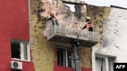 Specialists work on the facade of a damaged apartment building following a drone attack in Moscow, March 11, 2025.