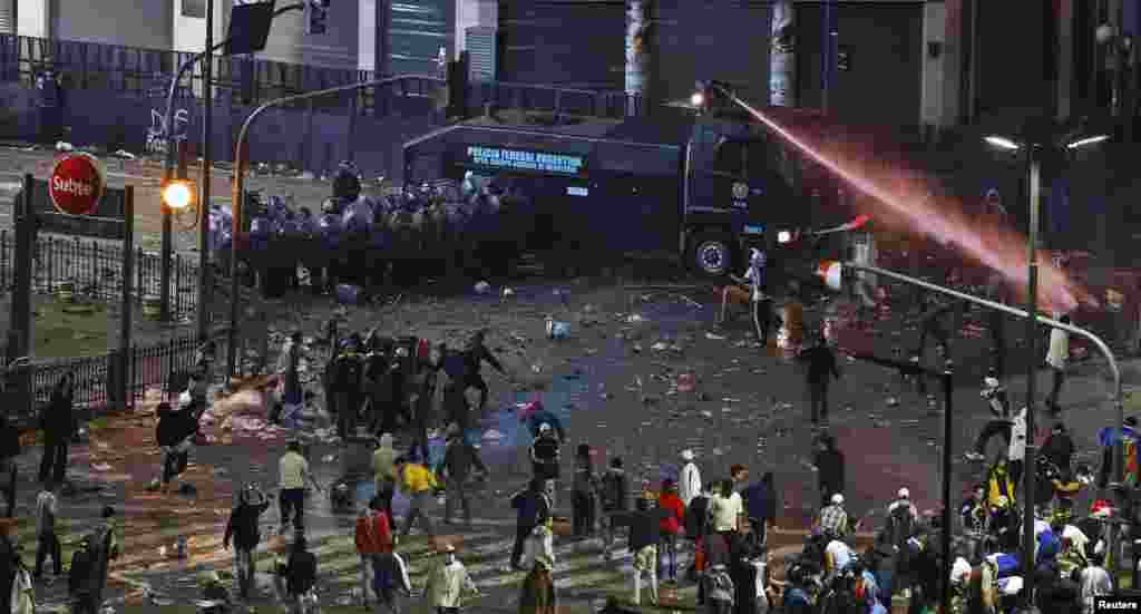 Riot police deploy a water canon on angry fans after Argentina lost to Germany in their 2014 World Cup final soccer match in Brazil, at a public square viewing area in Buenos Aires, July 13, 2014.