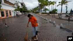 A city cleaner sweeps normal leaves and debris from a seafront walkway, the morning after Hurricane Patricia passed further south sparing Puerto Vallarta, Mexico, Oct. 24, 2015. 