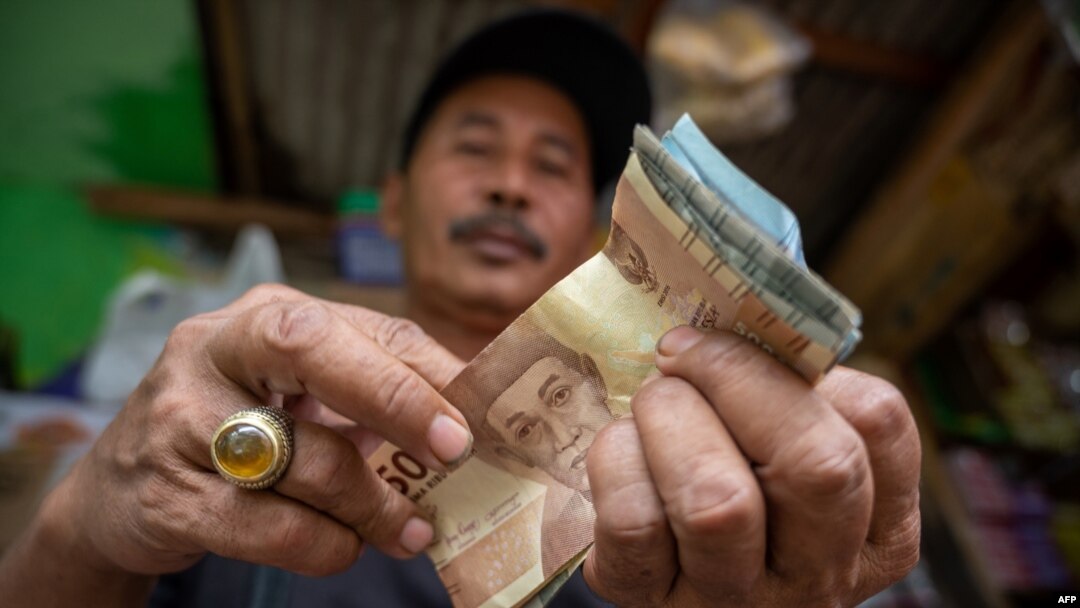 Seorang penjual makanan ringan menghitung uang hasil penjualannya yang jauh berkurang akibat pandemi Covid-19 di Jakarta. (Foto ilustrasi: AFP)