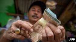 Seorang penjual makanan ringan menghitung uang hasil penjualannya yang jauh berkurang akibat pandemi Covid-19 di Jakarta. (Foto ilustrasi: AFP)