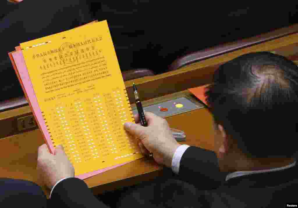 Seorang delegasi melihat kertas suara dalam sidang paripurna keempat Kongres Nasional Rakyat China di Beijing (14/3). (Reuters/Jason Lee)