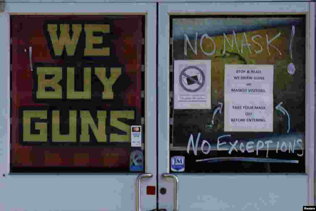 A sign on the door warning customers not to wear a face mask reads &quot;We Draw Guns on Masked Visitors&quot; at the 619DW Guns and Ammo store in Merrimack, New Hampshire, Nov. 29, 2021.