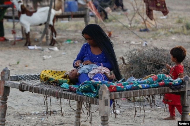 A woman, who became displaced, looks after her baby while taking refuge in a camp, following rains and floods during the monsoon season in Sehwan, Pakistan September 15, 2022. (REUTERS/Akhtar Soomro)