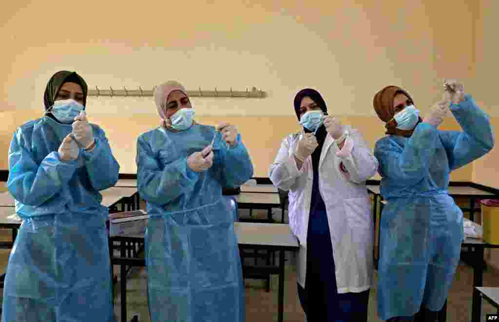 Palestinian health ministry workers prepare doses of the Sinopharm COVID-19 coronavirus vaccine, donated by the Chinese government, at a school in Halhoul, north of Hebron in the occupied West Bank.