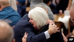 Texas Gov. Greg Abbott, left, hugs a woman as he visits with family and victims before a vigil, Nov. 8, 2017, in Floresville, Texas. A man opened fire inside a church in the small South Texas community of Sutherland Springs on Sunday, killing 26 wounding 20.