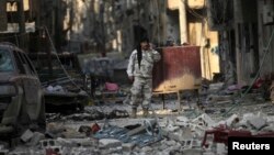 A Free Syrian Army fighter talks on a mobile phone as he stands on the rubble of damaged buildings in Deir al-Zor, eastern Syria, Nov. 12, 2013. 