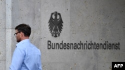 A picture taken on May 19, 2020 shows an employee walking past the name of German Federal Intelligence Service (BND) at its headquarters in Berlin. 