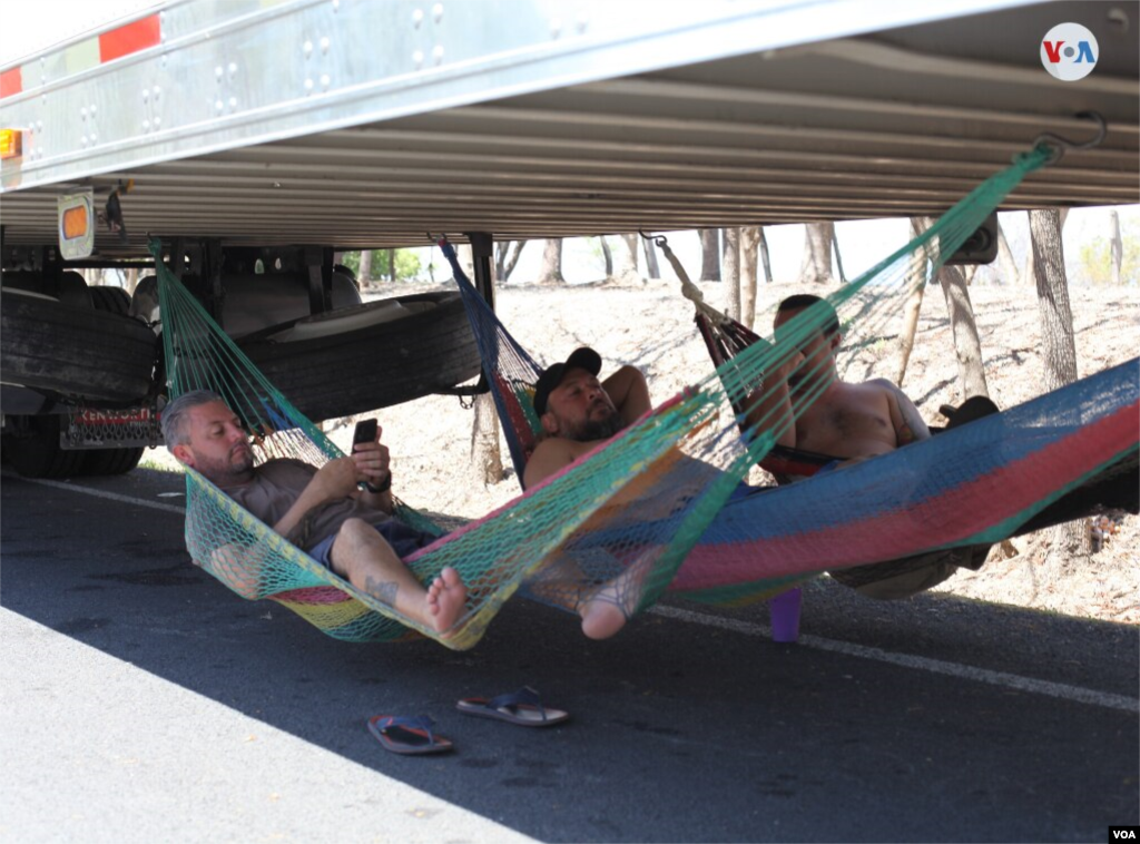 Los transportistas han colocado hamacas bajo los furgones para descansar durante el d&#237;a. 