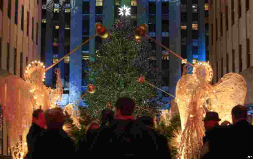 Pedestrians pass the Rockefeller Center Christmas tree after it was lit, Wednesday, Nov. 30, 2011, in New York. (AP Photo/Frank Franklin II)