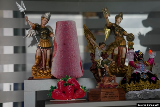 A cutout of a popsicle adorns a shelf next to a statue of patron saint Michael the Archangel in Salcedo, Ecuador, Thursday, Nov. 28, 2024. (AP Photo/Dolores Ochoa)