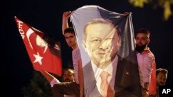 Men, holding a banner with a picture of Turkey's President Recep Tayyip Erdogan, celebrate outside his Justice and Development Party, or AKP, headquarters in Istanbul, June 24, 2018.