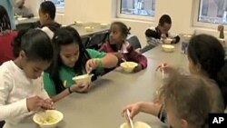 Students in the Kids Cafe after-school program learn about the nutritious value of an avocado while making an avocado and bean dip.