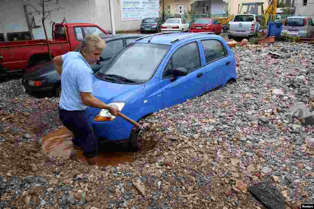 A local resident shovels mud blocking a car, following heavy rainfall in Malia on the island of Crete, Greece.